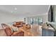 Bright living room featuring hardwood floors, a leather sofa set, and sliding glass doors to the sunroom at 118 Lake Sears Dr, Winter Haven, FL 33880