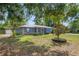 Cozy one-story home with a metal roof, screened porch, and a front yard framed by mature trees at 120 Bolender Rd, Auburndale, FL 33823