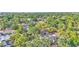 Aerial view of neighborhood, showcasing mature trees, nearby city, and a home with a private pool at 1421 Camphor Dr, Lakeland, FL 33803