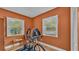 This room showcases an exercise bicycle, a table, wooden floors, and abundant natural light from its windows at 1421 Camphor Dr, Lakeland, FL 33803