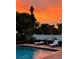Sunset poolside view featuring lounge chairs on brick patio next to serene pool and privacy fence at 1421 Camphor Dr, Lakeland, FL 33803
