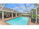 The screened-in pool area includes a brick patio, ample space for outdoor dining, and lush greenery for added privacy at 146 Woodside Dr, Lakeland, FL 33813