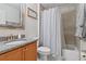 Bathroom with wooden cabinets, granite counters, a mirror, and shower with white and gray tile at 1519 Blue Sky Blvd, Haines City, FL 33844