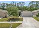 Charming single-story home with a well-manicured lawn, mature tree, and a two-car garage at 1825 Wallace Manor Ln, Winter Haven, FL 33880