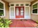 Inviting front entrance featuring double red doors, sidelights, transom windows, and lush plants creating a warm welcome at 236 E Seminole Ave, Lake Wales, FL 33853