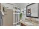Well-lit bathroom features a gray and white striped shower curtain and granite countertop sink at 242 Kings Pond Sw Ave, Winter Haven, FL 33880