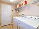 Bright laundry room featuring a full-size washer and dryer, shelving, and a door at 254 Lake Tennessee Dr, Auburndale, FL 33823