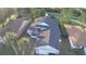 Aerial view showcases home's roof, screened lanai, manicured lawn, mature trees and corner lot at 432 Sandestin Dr, Winter Haven, FL 33884