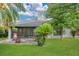 A screened-in patio, lush green lawn, mature trees, and landscaping create a serene and private backyard setting at 432 Sandestin Dr, Winter Haven, FL 33884