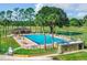 Community pool with lounge chairs and tables alongside lush greenery and mature trees at 432 Sandestin Dr, Winter Haven, FL 33884