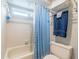 Bright bathroom featuring tile flooring, white tiled walls, and tub with a new blue shower curtain at 4825 Luce Rd, Lakeland, FL 33813