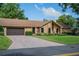 Brick home featuring a paved driveway leading to an attached garage, surrounded by lush greenery at 4825 Luce Rd, Lakeland, FL 33813