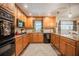 Spacious kitchen featuring wooden cabinets, black appliances, granite countertops, and a stylish area rug at 4825 Luce Rd, Lakeland, FL 33813