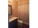This cozy bathroom includes a dark vanity with a light countertop, a toilet, and a shower with a floral shower curtain at 5619 Antler Trl, Lakeland, FL 33811
