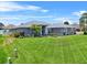Well-manicured lawn and landscaping enhance this home's curb appeal, with a beautiful blue sky backdrop at 647 Hart Lake Dr, Winter Haven, FL 33884
