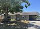 Single-story home showing covered carport, small garden, and a large shade tree in the front yard at 6610 Chippendale Rd, Lakeland, FL 33809