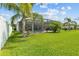 Spacious backyard featuring lush green lawn, palm trees, screened lanai, offering a private outdoor retreat at 6777 Bentridge Dr, Lakeland, FL 33813
