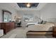 Spacious bedroom with tray ceiling, ceiling fan, and a full size bed next to a large dresser and desk at 6777 Bentridge Dr, Lakeland, FL 33813