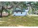 The home features white siding, a green metal roof covered with leaves, and a spacious lawn at 6949 2Nd St, Mulberry, FL 33860