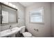 Cozy bathroom with gray walls, a framed mirror, a sink, a toilet, and a window at 707 Laurel Pointe Ct, Lakeland, FL 33813