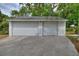 Two-car garage with white siding and concrete driveway surrounded by mature trees at 716 S Franklin Pl, Lakeland, FL 33815
