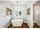 Bathroom with free-standing tub, wood floors, modern light fixture, and white walls at 717 Frank Lloyd Wright Way, Lakeland, FL 33803