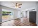 Bright living room with wood floors, ceiling fan, sliding door, and stainless steel refrigerator at 717 Frank Lloyd Wright Way, Lakeland, FL 33803