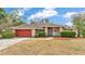 Charming one-story home with a red garage door and manicured landscaping at 7741 Merrily Way, Lakeland, FL 33809