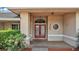 Close-up of the front entrance with double doors, decorative window and lush landscaping at 7741 Merrily Way, Lakeland, FL 33809