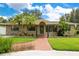 Charming single-story home with brick walkway, lush lawn, beautiful tropical landscaping, and inviting front entrance at 865 E Mann Rd, Bartow, FL 33830