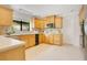 Well-lit kitchen with cream tile floors, wood cabinets, stainless steel appliances, and a window overlooking greenery at 865 E Mann Rd, Bartow, FL 33830