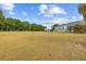 Spacious fenced-in backyard with expansive lawn area, tree line, and view of rear of house at 8909 N Campbell Rd, Lakeland, FL 33810