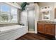 Bathroom featuring a soaking tub, glass shower, and wood vanity with a granite countertop and shuttered window at 8909 N Campbell Rd, Lakeland, FL 33810