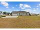 Rear exterior view of the home with a three car garage and well-maintained backyard at 8909 N Campbell Rd, Lakeland, FL 33810