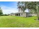 Grassy backyard with views of the home's exterior and covered patio at 1001 Lena Run Ct, Winter Haven, FL 33880