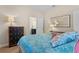 Cozy bedroom featuring a blue patterned quilt, decorative mirror, and a peek into the en-suite bathroom at 1001 Lena Run Ct, Winter Haven, FL 33880
