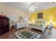 Bright bedroom featuring wood floors, decorative rug, white furniture and a contrasting yellow accent wall at 1056 Rally Dr, Polk City, FL 33868