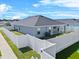 Backyard view of home featuring a white vinyl fence, green lawn, and outdoor HVAC unit under a partly cloudy blue sky at 1106 Tropea Ln, Auburndale, FL 33823