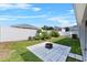Private backyard featuring a paver patio with a fire pit, surrounded by a white fence and green landscaping at 1106 Tropea Ln, Auburndale, FL 33823