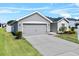 Exterior view of gray home with a two-car garage and concrete driveway, green lawn, and neatly trimmed bushes at 1106 Tropea Ln, Auburndale, FL 33823