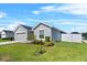 Well-kept front yard with green lawn and landscaping, complemented by the home's light gray exterior and two-car garage at 1106 Tropea Ln, Auburndale, FL 33823