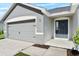 Home exterior showcasing a two-car garage, a gray front door, and a well-maintained walkway at 1106 Tropea Ln, Auburndale, FL 33823