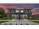 Modern duplex featuring dual two-car garages, manicured lawns, and a shared driveway at dusk at 1171 Windjammer Dr, Lakeland, FL 33803