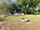 View of backyard with chain link fence, above ground pool, fire pit, grass and trees at 135 E Columbia St, Lake Alfred, FL 33850