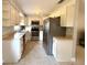 Traditional kitchen featuring white cabinetry, stainless steel appliances, and speckled flooring, offering a functional space at 135 E Columbia St, Lake Alfred, FL 33850