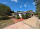 Exterior view of a charming single-story home with mature trees, landscaped lawn, and brick walkway at 16 Golfview Ne Cir, Winter Haven, FL 33881