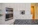 Bright kitchen featuring built-in ovens, white cabinetry, and a stylish tile backsplash at 16 Golfview Ne Cir, Winter Haven, FL 33881