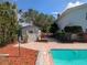 View of the pool and the shed in a yard featuring an in-ground pool, landscaping, and a white shed at 16 Golfview Ne Cir, Winter Haven, FL 33881