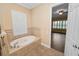 Bathroom showcasing a tiled tub, window with plantation shutters, and neutral color scheme at 1772 Laurel Glen Pl, Lakeland, FL 33803