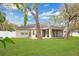 Well-manicured backyard with mature trees, green lawn, and home featuring a screened-in patio at 1837 Farrington Dr, Lakeland, FL 33809